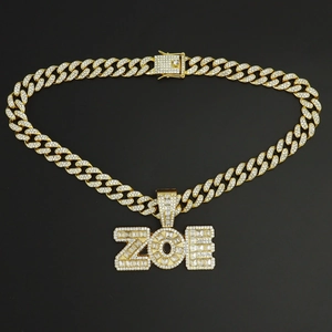 Detalle de cadena cubana dorada con colgante de letras ZOE y circonitas engastadas