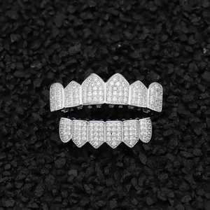 Macro shot of silver hip hop grillz with shimmering cubic zirconia on black stone texture