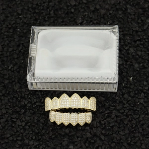 Gold hip hop grillz set with zircon stones on a dark textured background in a clear box