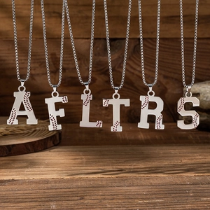 Silver stainless steel baseball letter necklace featuring red stitch detail on wooden background