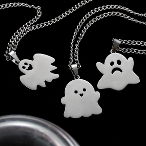 Close-up of three polished stainless steel ghost pendants with various facial expressions