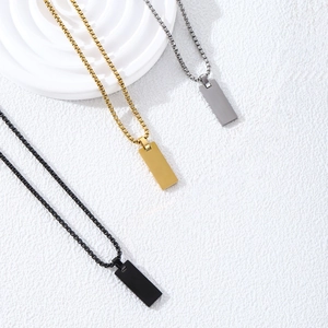 Minimalist rectangular pendant necklaces in gold, silver, and black on a textured display