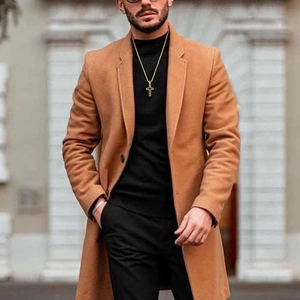 Close-up of men's hollow gold cross necklace styled with a camel overcoat and black knit