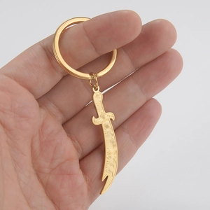 Detail of vintage golden scimitar keychain with embossed patterns held in hand