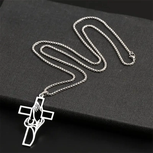 Polished stainless steel cross necklace with engraved praying hands on a box chain