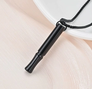 Detail view of a matte black mindfulness whistle pendant on a delicate chain necklace