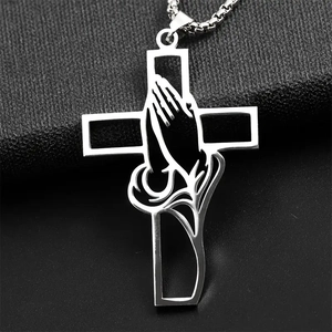 Close-up of a silver stainless steel hollow cross necklace with praying hands on black fabric