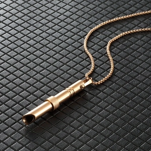Detail view of rose gold mindfulness whistle pendant on black quilted leather background