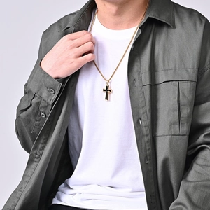 Polished gold stainless steel cross pendant necklace displayed on a casual male outfit