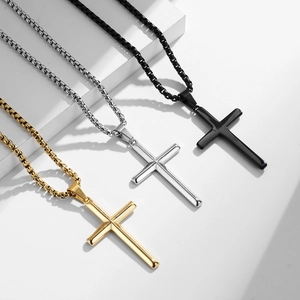 Three-color stainless steel cross necklaces in gold, silver, and black on geometric props
