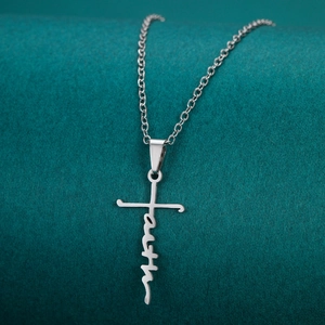 Polished stainless steel cross necklace with faith lettering on dark velvet background