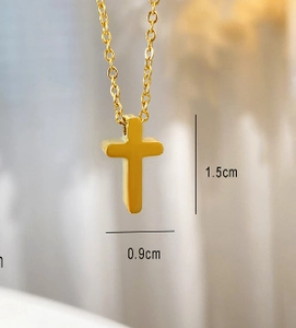 Gros plan montrant les dimensions de 1,5cm sur 0,9cm de ce pendentif croix dorée