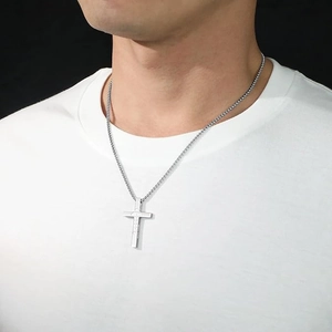 Détail du pendentif croix en acier inoxydable argenté avec texte gravé sur t-shirt