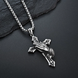 Vintage stainless steel cross necklace with praying hands pendant on black stone background
