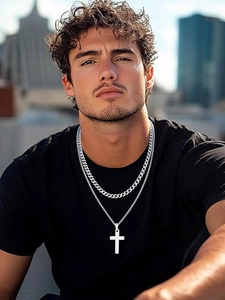 Close-up of double-layered silver Cuban link necklace with cross pendant on male model