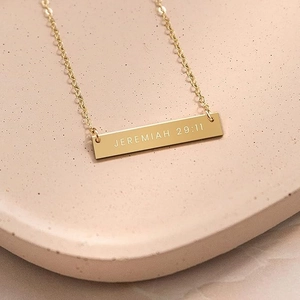 Gold stainless steel bar necklace with Jeremiah 29:11 engraving on a beige plate