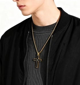 Dettaglio di un uomo che indossa una collana a croce in acciaio bicolore oro e nero