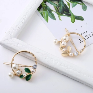 Barrettes rondes élégantes avec perles, strass et feuilles sur un fond décoratif