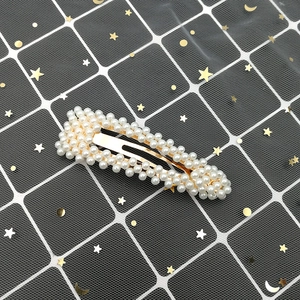 Detail of elegant rectangular hair clip with white faux pearls on golden base