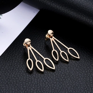 Minimalist gold hollow teardrop earrings with a three-leaf design on black leather backdrop