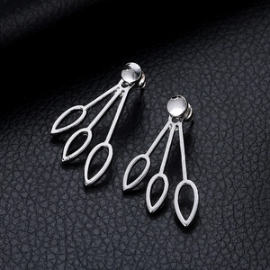 Macro shot of silver minimalist hollow teardrop earrings on black leather texture
