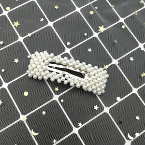 Detailed view of rectangular pearl hair clip with white pearls on silver metal base
