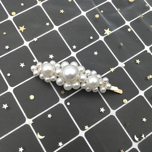 Macro detail of elegant oval hair clip featuring white pearls on a gold metal base