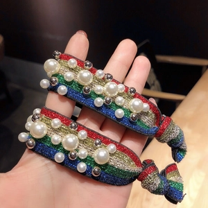 Close-up of rainbow striped hair ties with faux pearls and metallic bead accents