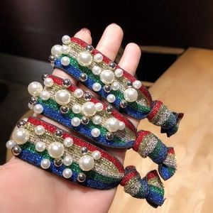 Detail of three rainbow striped elastic hair ties with pearls and silver metallic beads