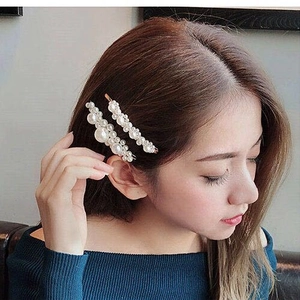 Elegant set of two gold-plated hair clips with white pearls worn on brown hair