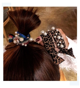 Detail of leopard print scrunchie and rainbow glitter hair tie with pearl accents