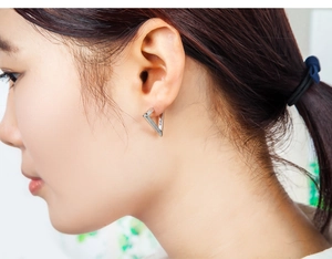 Close-up detail of silver hollow star geometric earring on ear with polished finish
