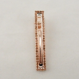 Dettaglio del fermaglio per capelli rettangolare con strass marroni e base in oro rosa