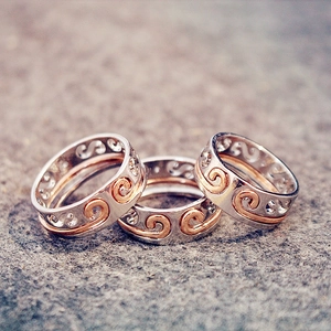 Macro view of silver and rose gold rings featuring hollow swirl wave patterns