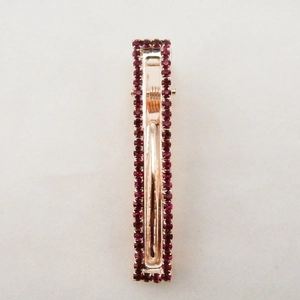 Vista macro della clip rettangolare in oro rosa con doppia fila di strass rosso scuro