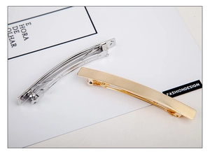Detail of minimalist rectangular metal spring hair clips in polished gold and silver finishes