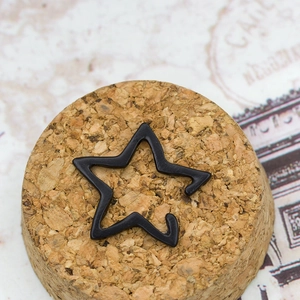 Minimalist matte black star ear cuff with hollow geometric lines on a vintage cork base