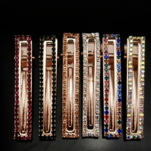 Dettaglio di sei fermagli rettangolari con strass in colori assortiti su base in lega dorata