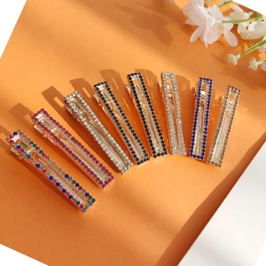 Otto fermagli per capelli rettangolari con strass colorati su uno sfondo arancione