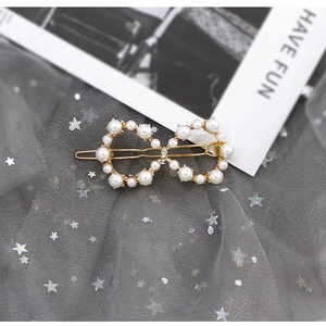 Dettaglio di un fermaglio per capelli con perle, base in lega dorata e piccoli strass