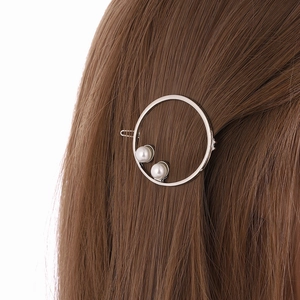 Silver circular metal hair clip with dual white pearls on elegant dark brown hair
