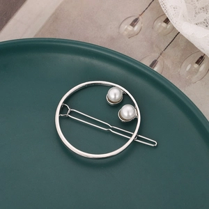Minimalist silver circular hair clip with double pearls on a dark green background