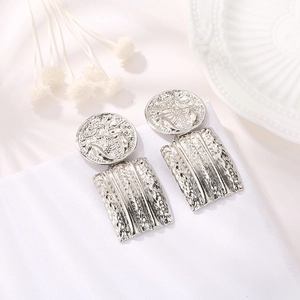 Silver vintage coin drop earrings with geometric textured rectangle pendants in a still life