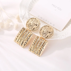 Detailed close-up of retro gold geometric earrings with hammered texture and floral relief