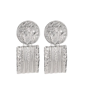 Detail of silver geometric earrings with embossed coins and textured wavy rectangle pendants