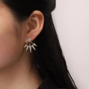 Gros plan sur des boucles d'oreilles ear jacket dorées avec strass blancs brillants