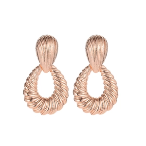 Detail of rose gold alloy earrings featuring spiral water drop texture on white background