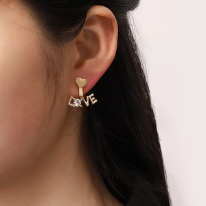 Detail von goldenen Herzohrringen mit LOVE-Schriftzug und Strass an einem Modell
