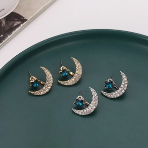 Star and moon stud earrings set with white rhinestones and blue crystals in gold and silver