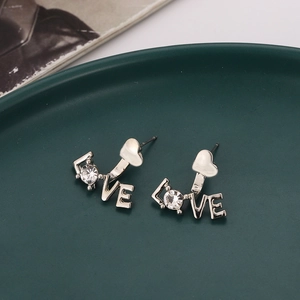 Silberne LOVE Herz-Ohrstecker mit Zirkonia auf einem grünen Dekoteller präsentiert